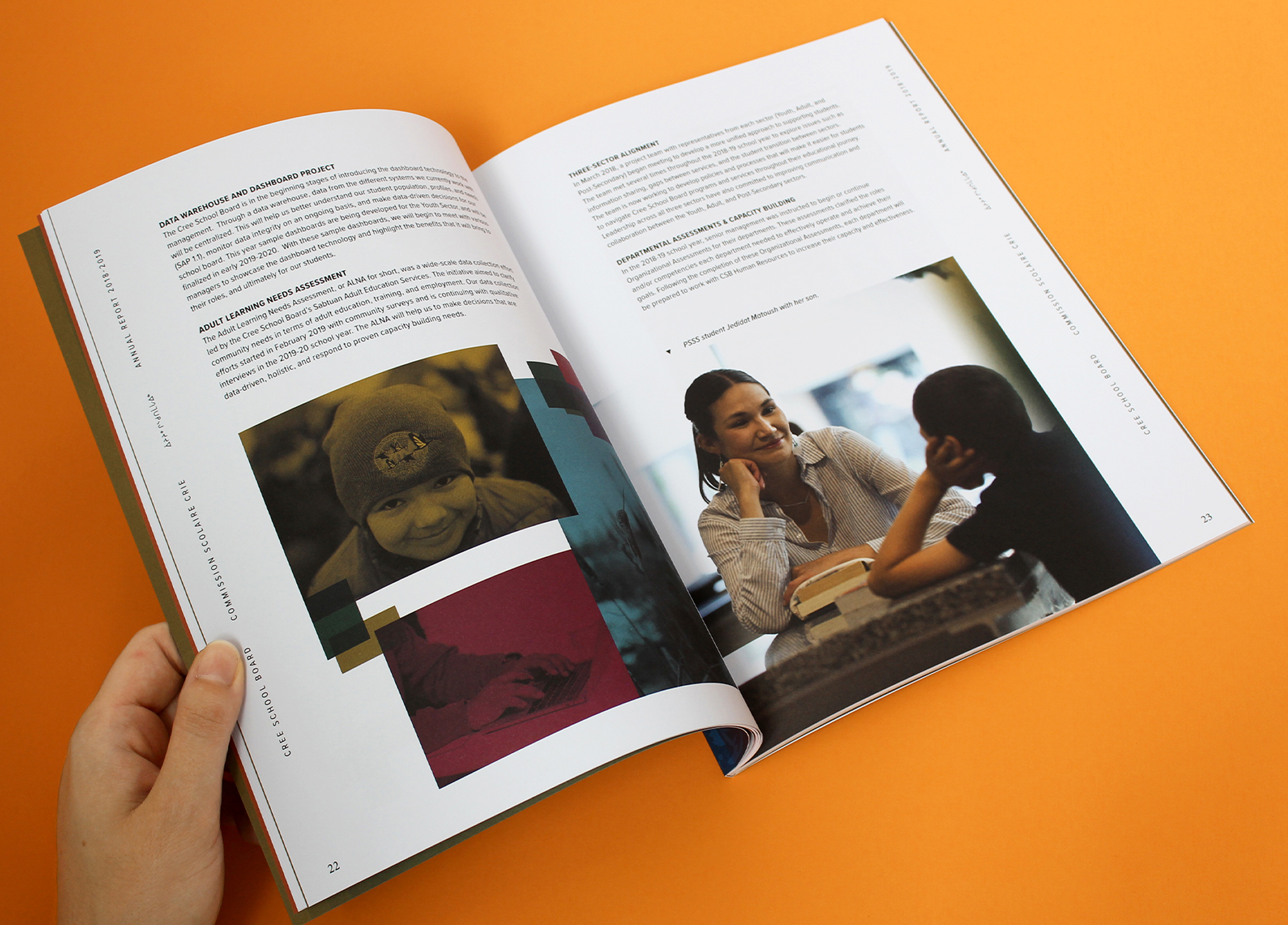 CSB_201819_Body-4 A hand holds open a magazine on an orange surface, showing pages with text and photos of people; one page features a woman smiling across a table from another person, and the other shows a person in winter clothing.