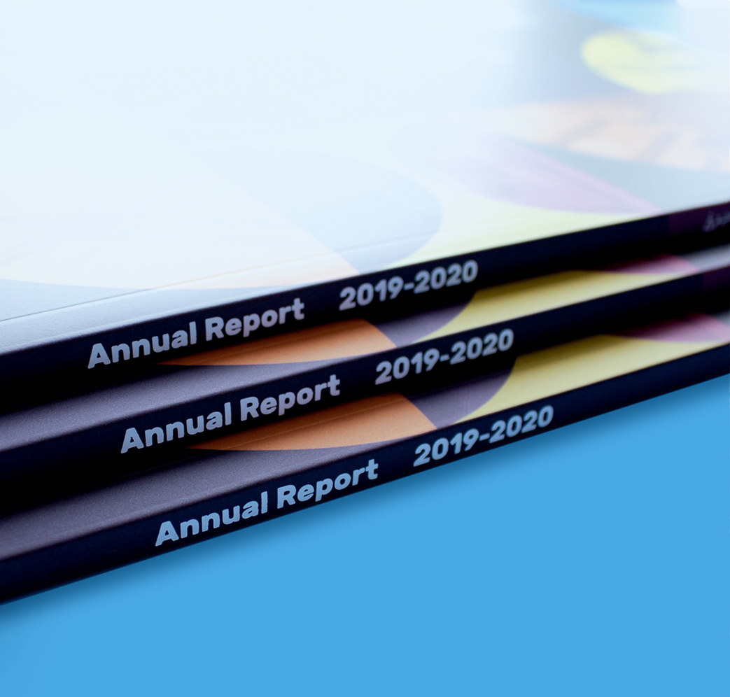 CSB_201920_Body-2 Three annual report booklets for 2019-2020 are stacked on a blue surface, with the spines facing outward showing the title “Annual Report 2019-2020” in white text.