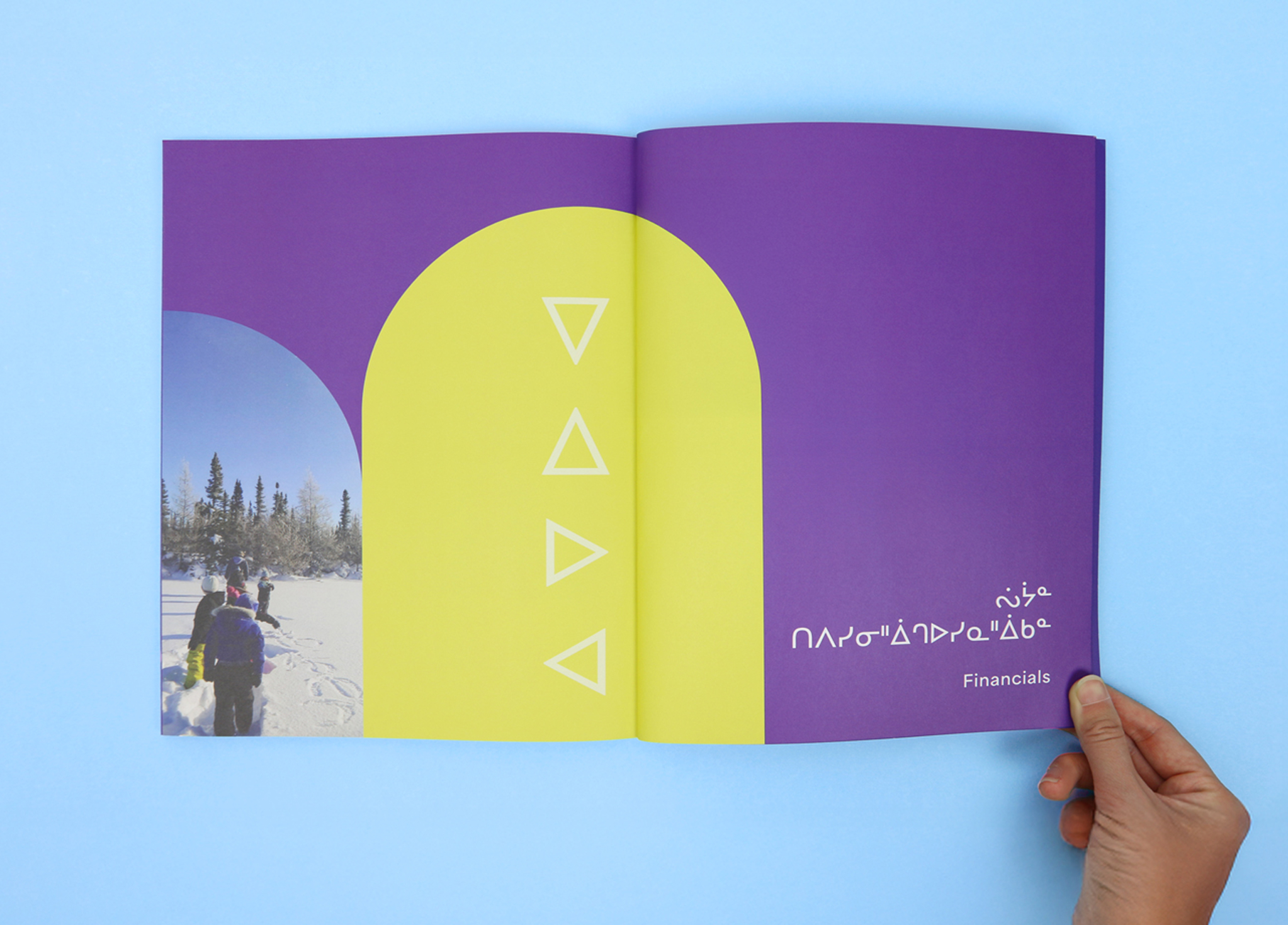 CSB_202223_Body-4 An open booklet displays a snowy outdoor scene with people on the left page and a bold yellow and purple design with white triangle symbols and the word