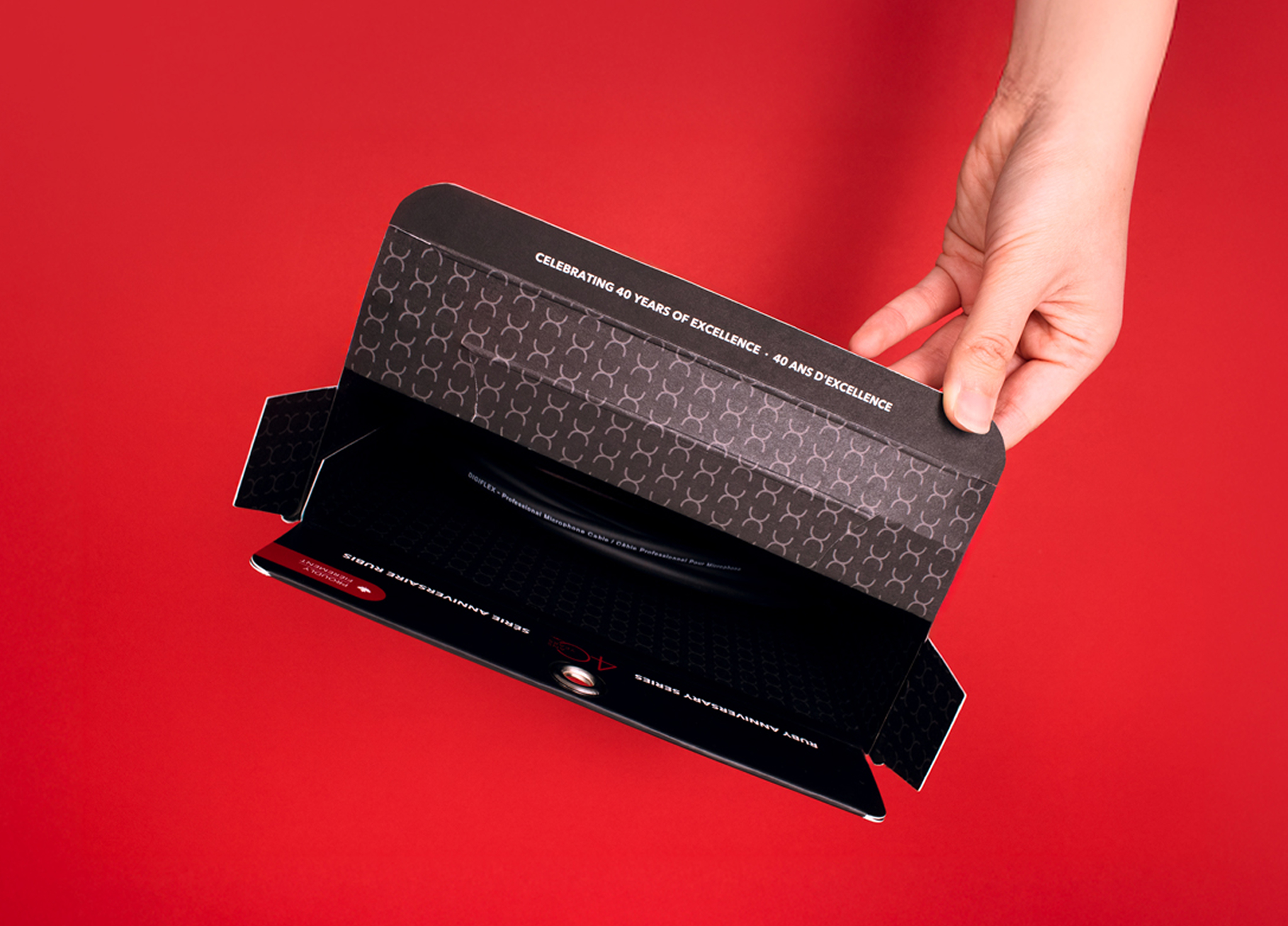 Digiflex-4 A hand holds an open black envelope with a geometric pattern and text that reads,