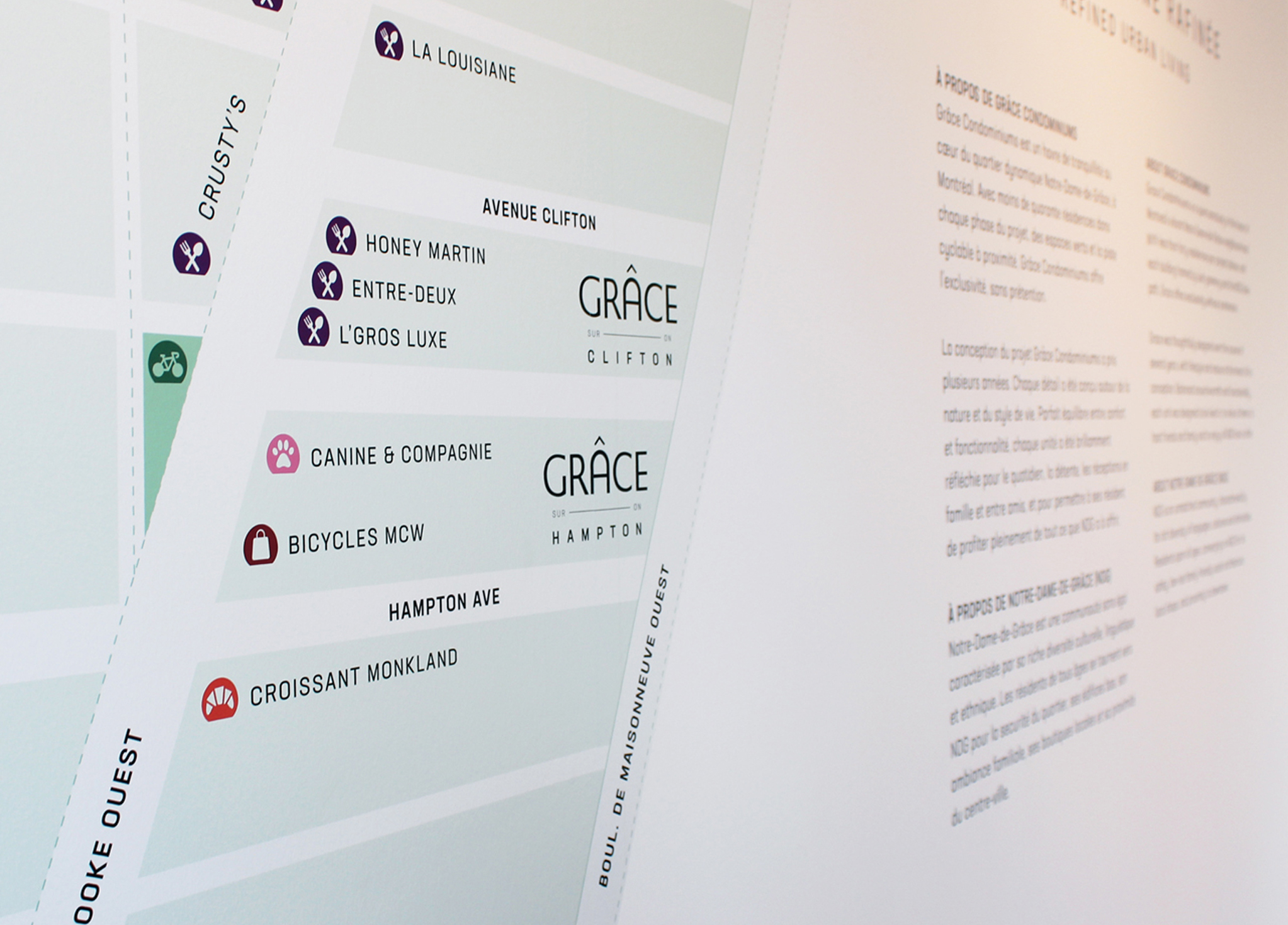 Grace_6 A close-up of a directional map with locations and icons listed, such as Honey Martin, Croissant Monkland, and GRÂCE Clifton, alongside French text on a white wall.