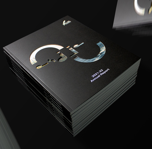 A stack of black annual reports with a metallic, cut-out design on the cover and white text that reads
