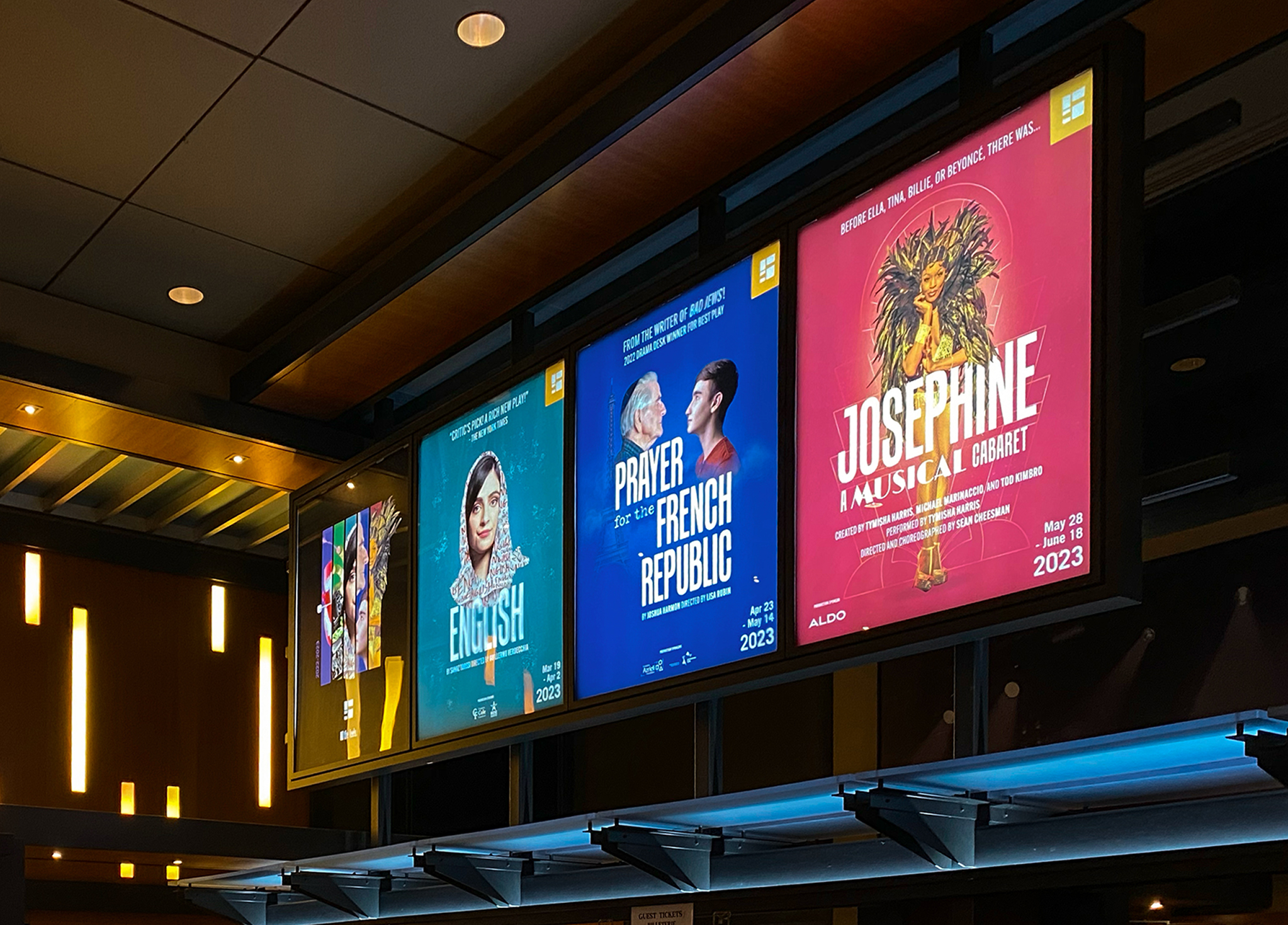 Segal_202223-1 Four colorful theater posters are displayed above a box office. The posters advertise different productions, including “English,” “Prayer for the French Republic,” and “Josephine: A Musical Cabaret.”.