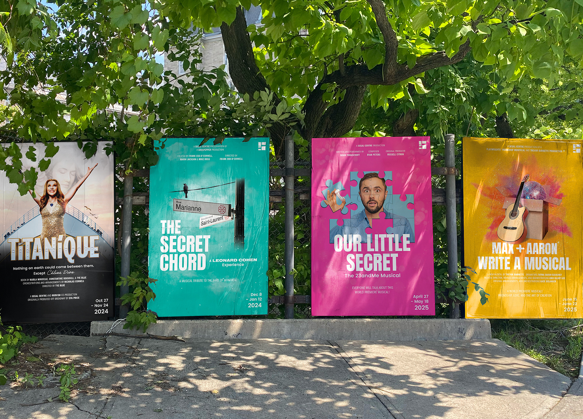 Segal_202425-1 Four colorful theatre posters are displayed outdoors on a fence under leafy trees, advertising shows titled