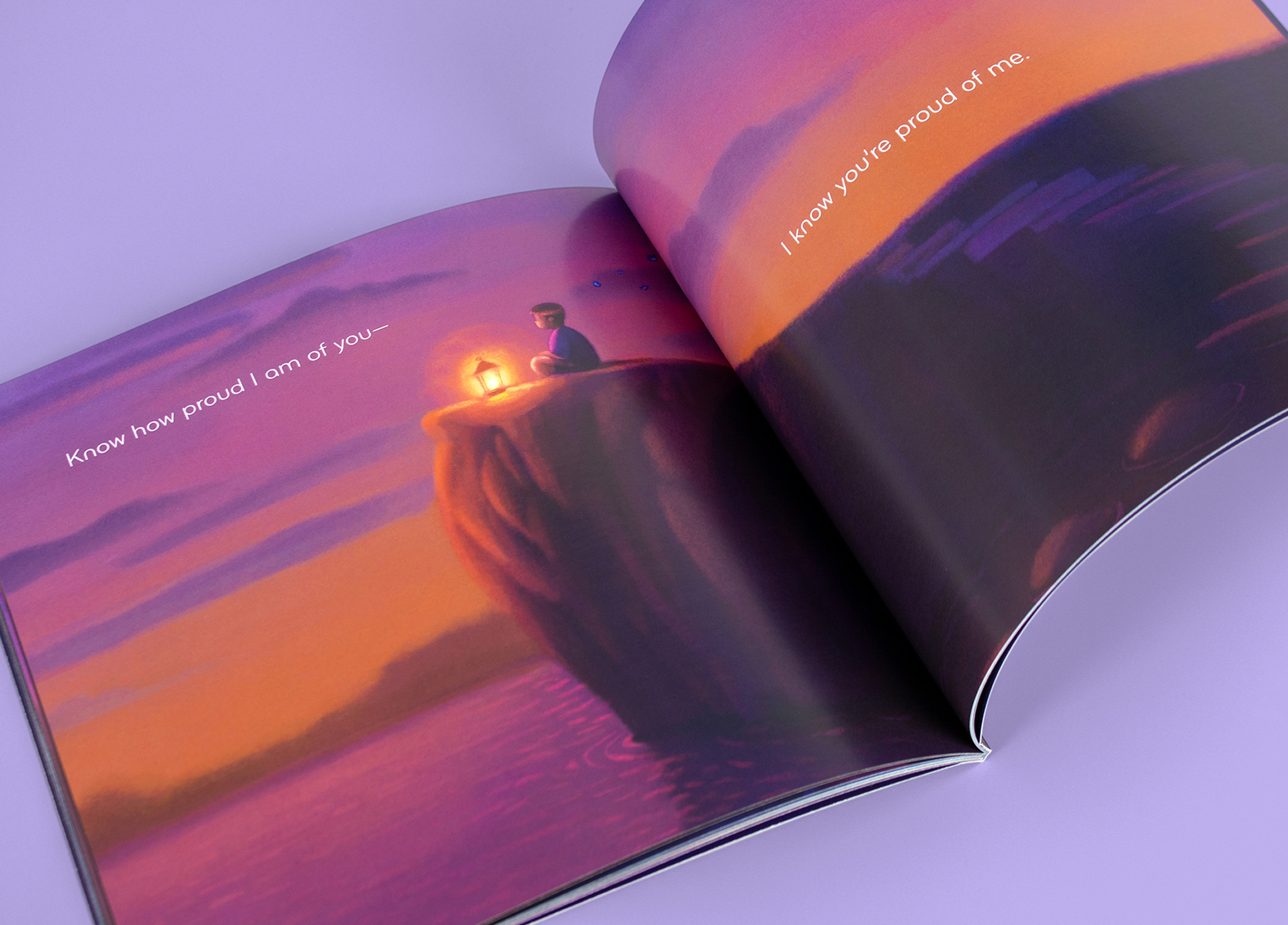 An open illustrated book shows a person sitting on a cliff with a lantern, overlooking a calm body of water at sunset. Text on the pages reads,