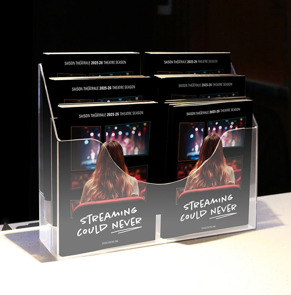 A clear brochure holder displays theater season booklets featuring a woman watching a stage from behind. The cover reads “STREAMING COULD NEVER.” The brochures promote the 2025-26 theatre season.